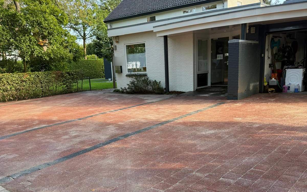 Gereinigde oprit van rode klinkers bij een woning