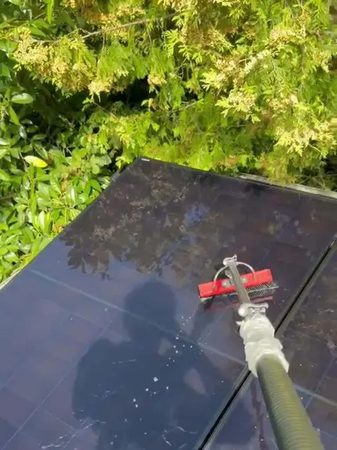 Zonnepaneel wordt gereinigd met een borstel aan een lange steel